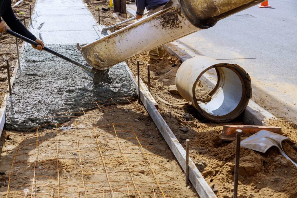 Workers are pouring concrete and resurfacing concrete sidewalk