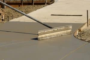 Worker resurfacing newly installed concrete sidewalk
